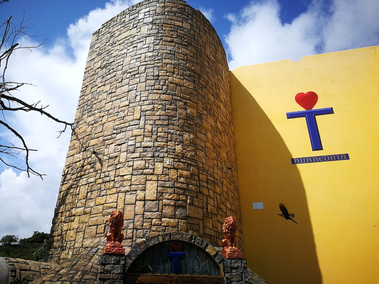 Torre revestida con piedra Hackett Montaña Amarilla, contra un muro amarillo
