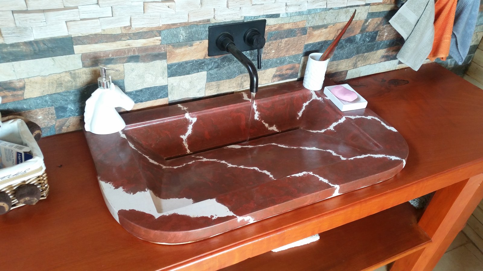 Lavamanos Florentina de concreto rojo con vetas blancas, instalado y en uso