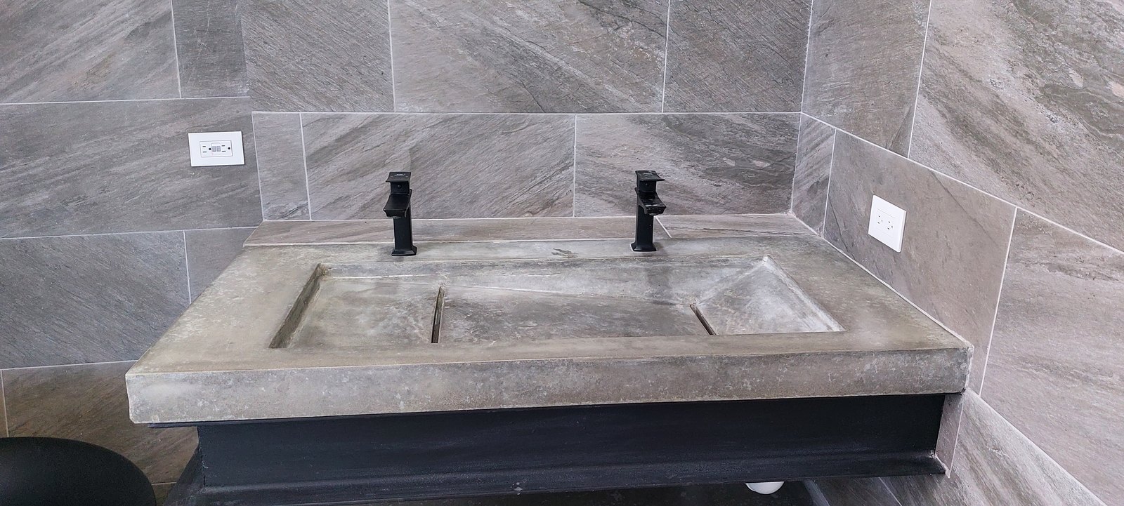 Lavamanos doble de concreto gris con dos grifos negros